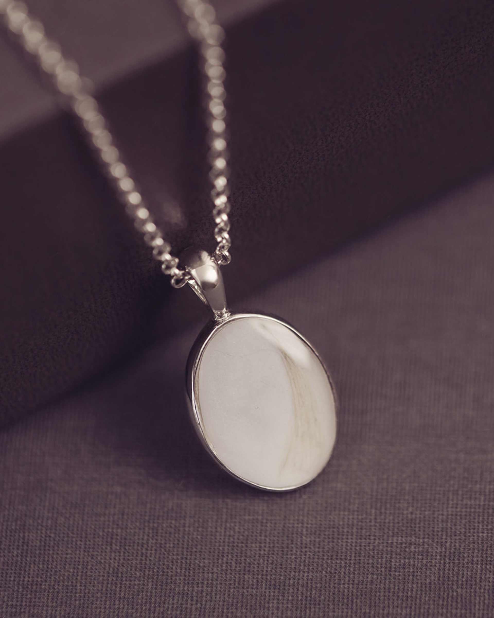 Necklace with a white pendant on a purple fabric background