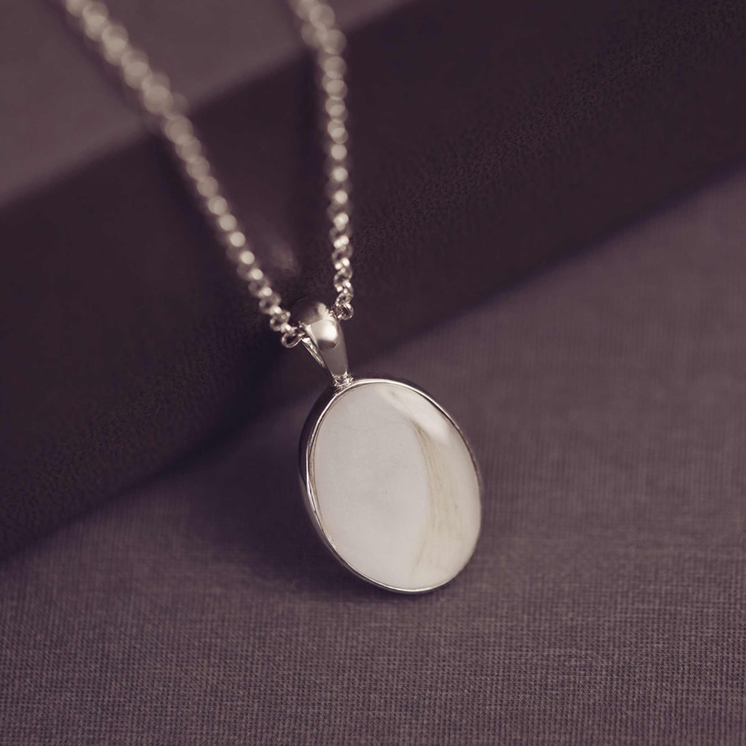 Necklace with a white pendant on a purple fabric background