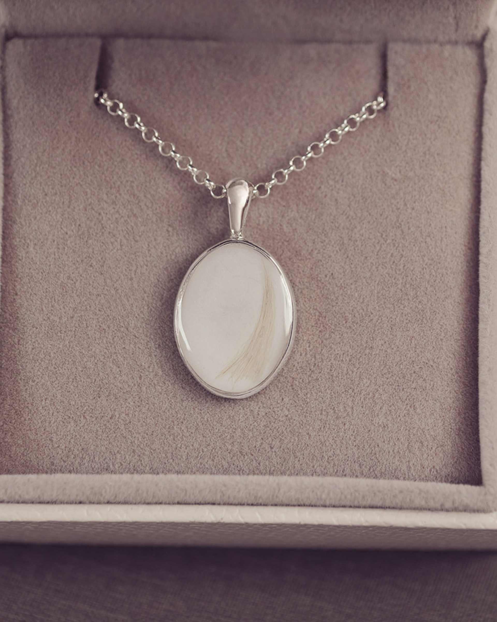 Silver necklace with a pendant on a gray cushioned jewelry box