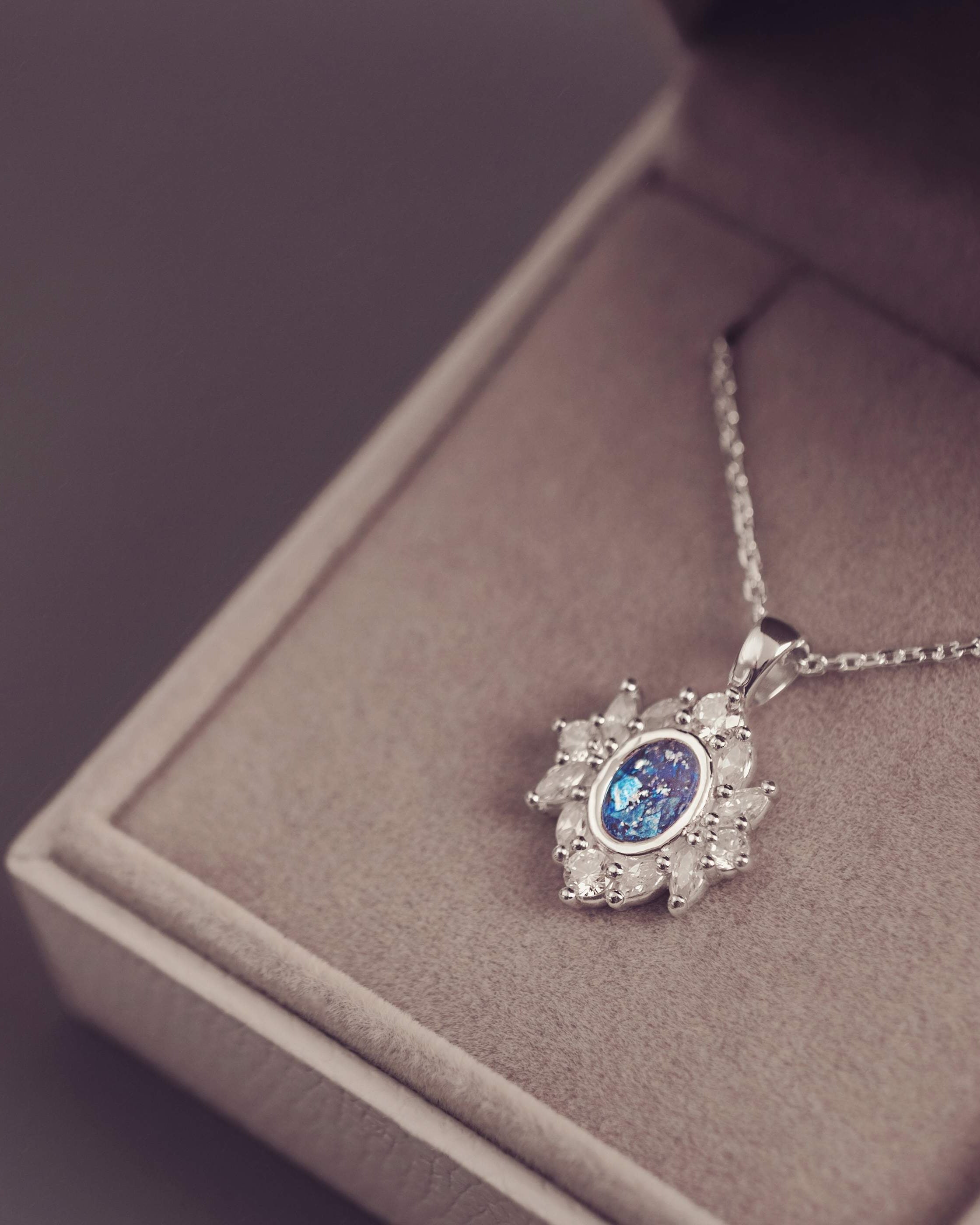 Silver necklace with a blue gemstone pendant on a gray surface