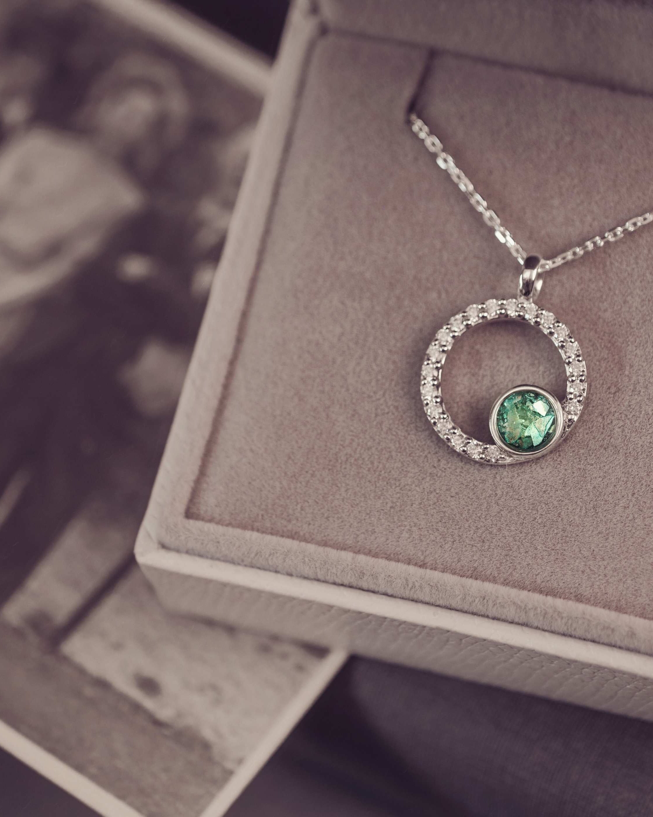 Silver necklace with a green gemstone pendant on a jewelry box.