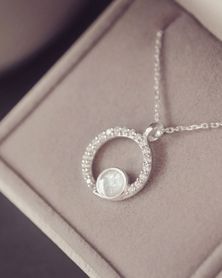 Silver necklace with a circular pendant on a soft surface