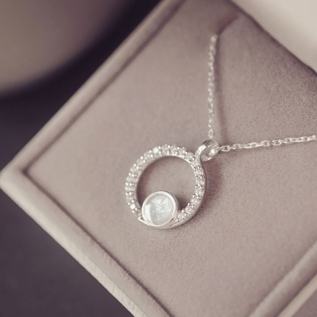 Silver necklace with a circular pendant on a soft surface