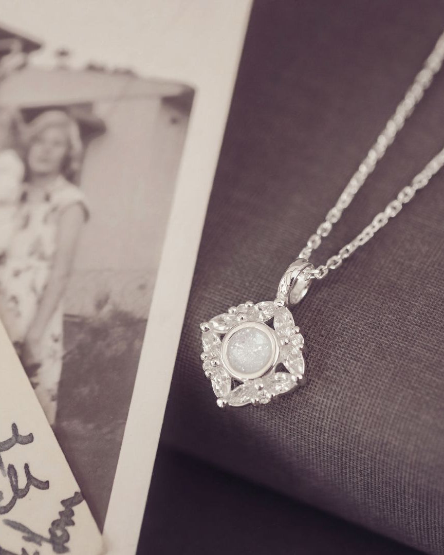 Silver necklace with a pendant next to an old photograph on a textured surface