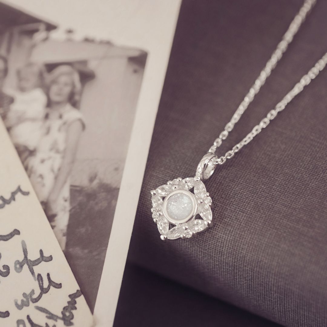 Silver necklace with a pendant next to an old photograph on a textured surface