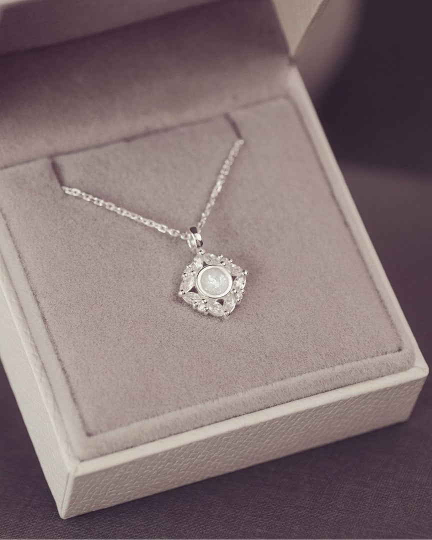 Silver necklace with a pendant in an open jewelry box on a purple background