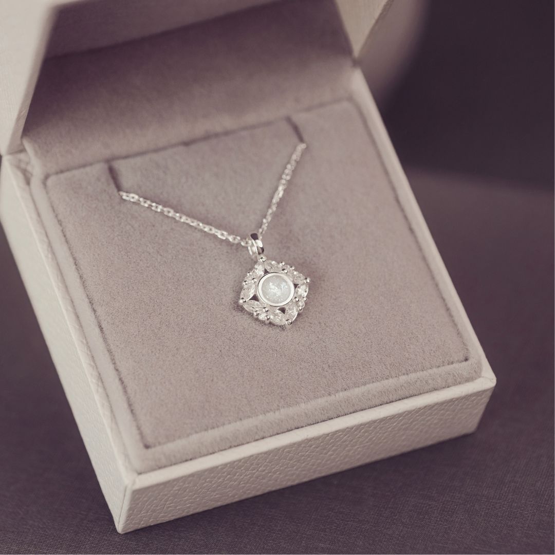 Silver necklace with a pendant in an open jewelry box on a purple background
