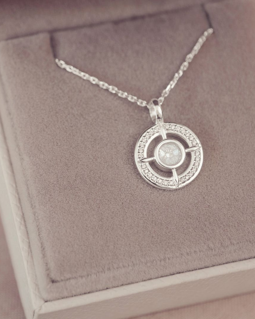 Silver necklace with a circular pendant on a pink jewelry box