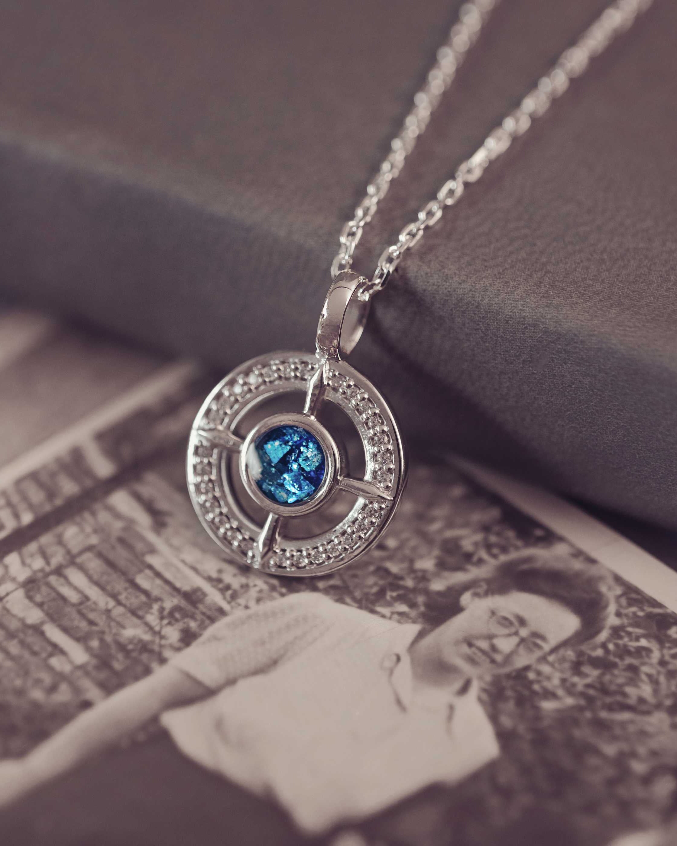 Silver necklace with a blue gemstone pendant on a vintage book