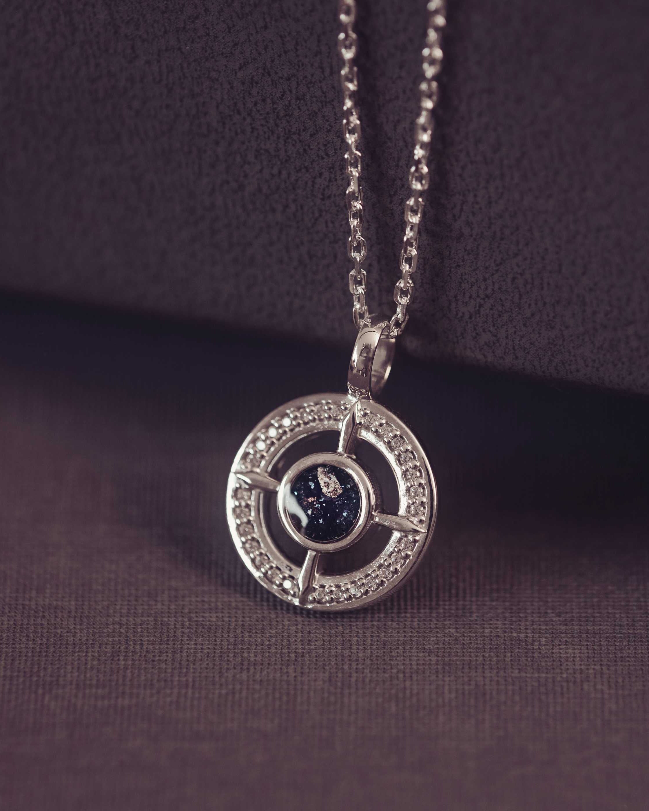Silver necklace with a circular pendant on a dark purple background