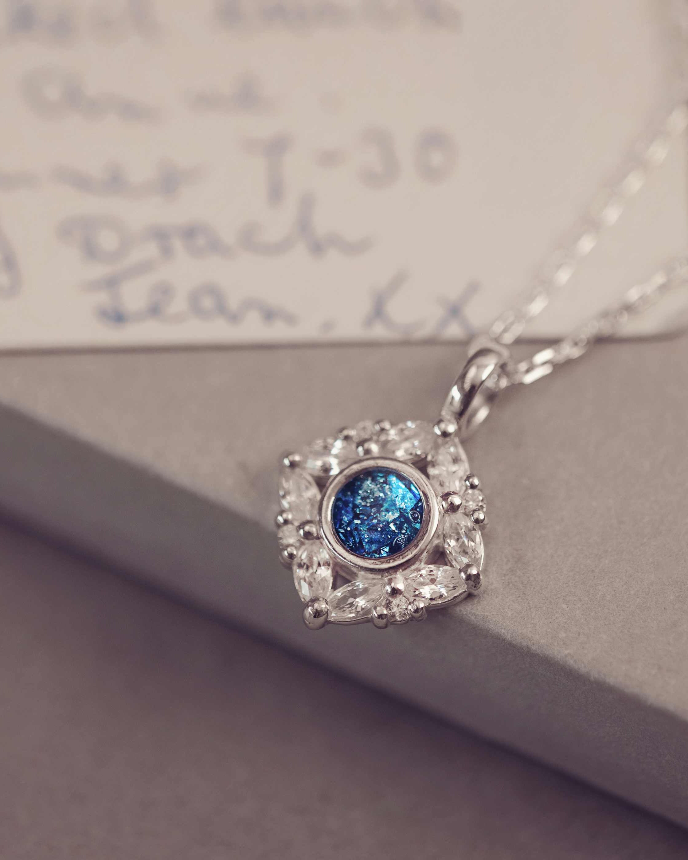 Silver necklace with a blue gemstone pendant on a textured surface