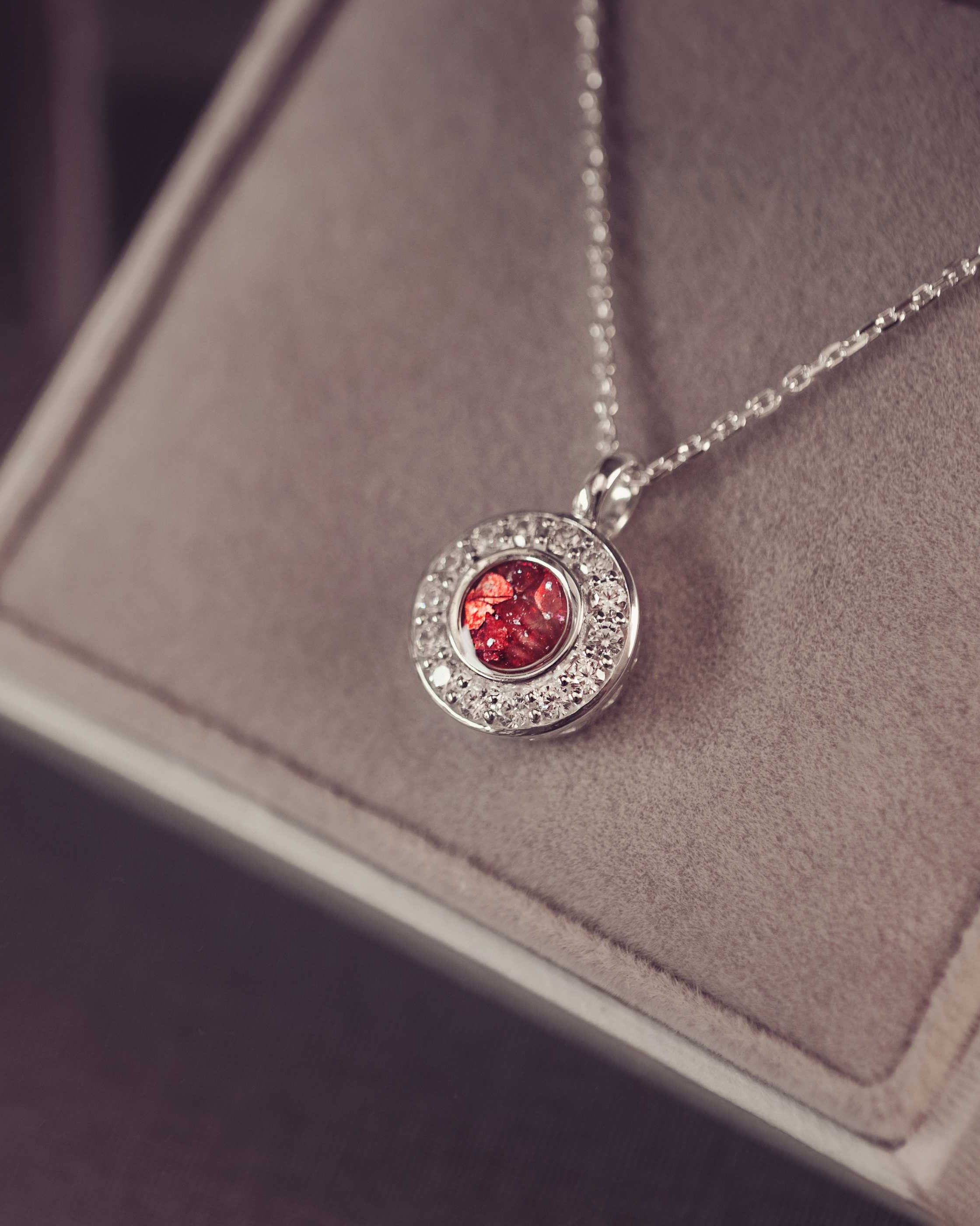 Silver necklace with a red gemstone pendant on a gray surface