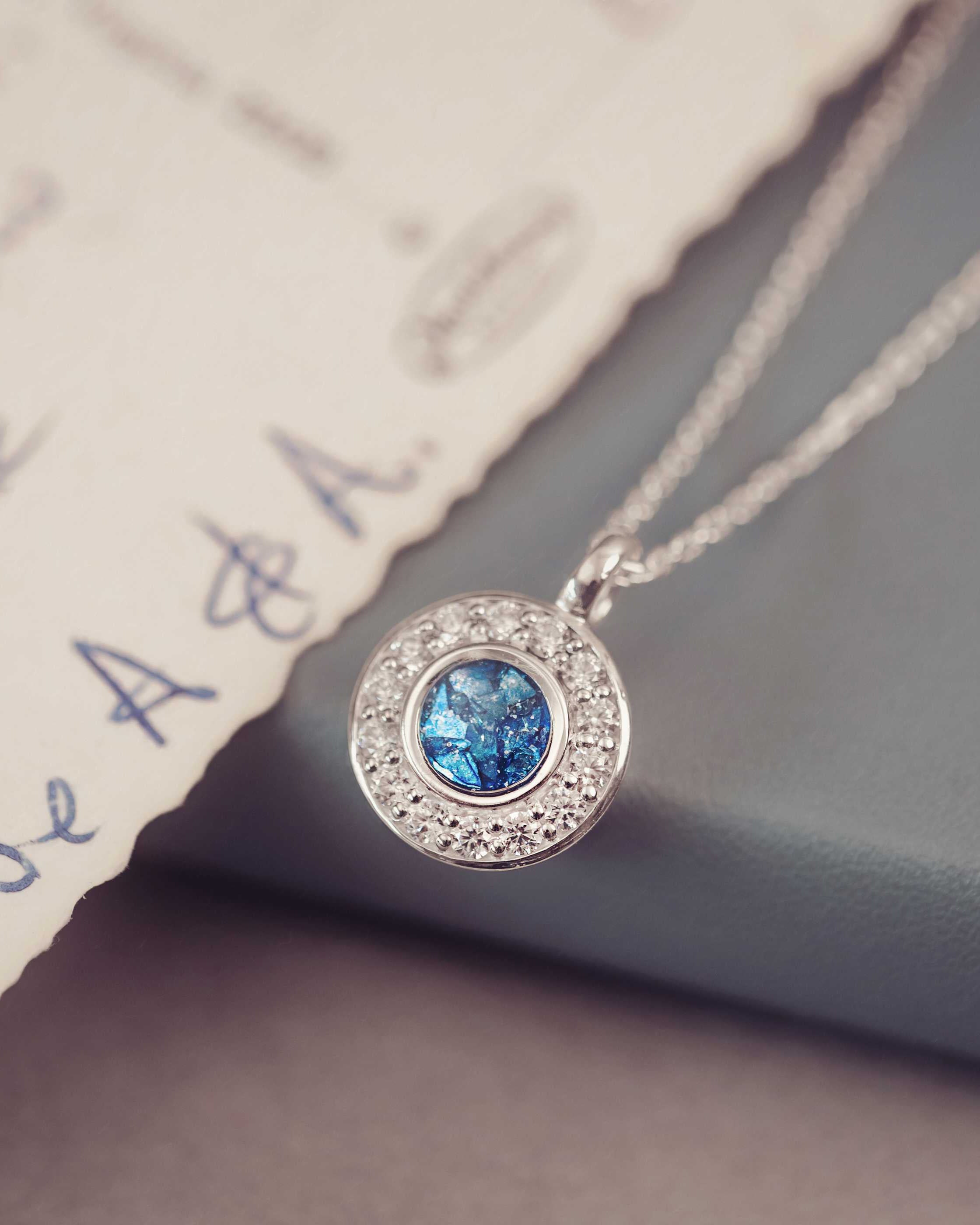 Silver necklace with a blue gemstone pendant on a textured surface