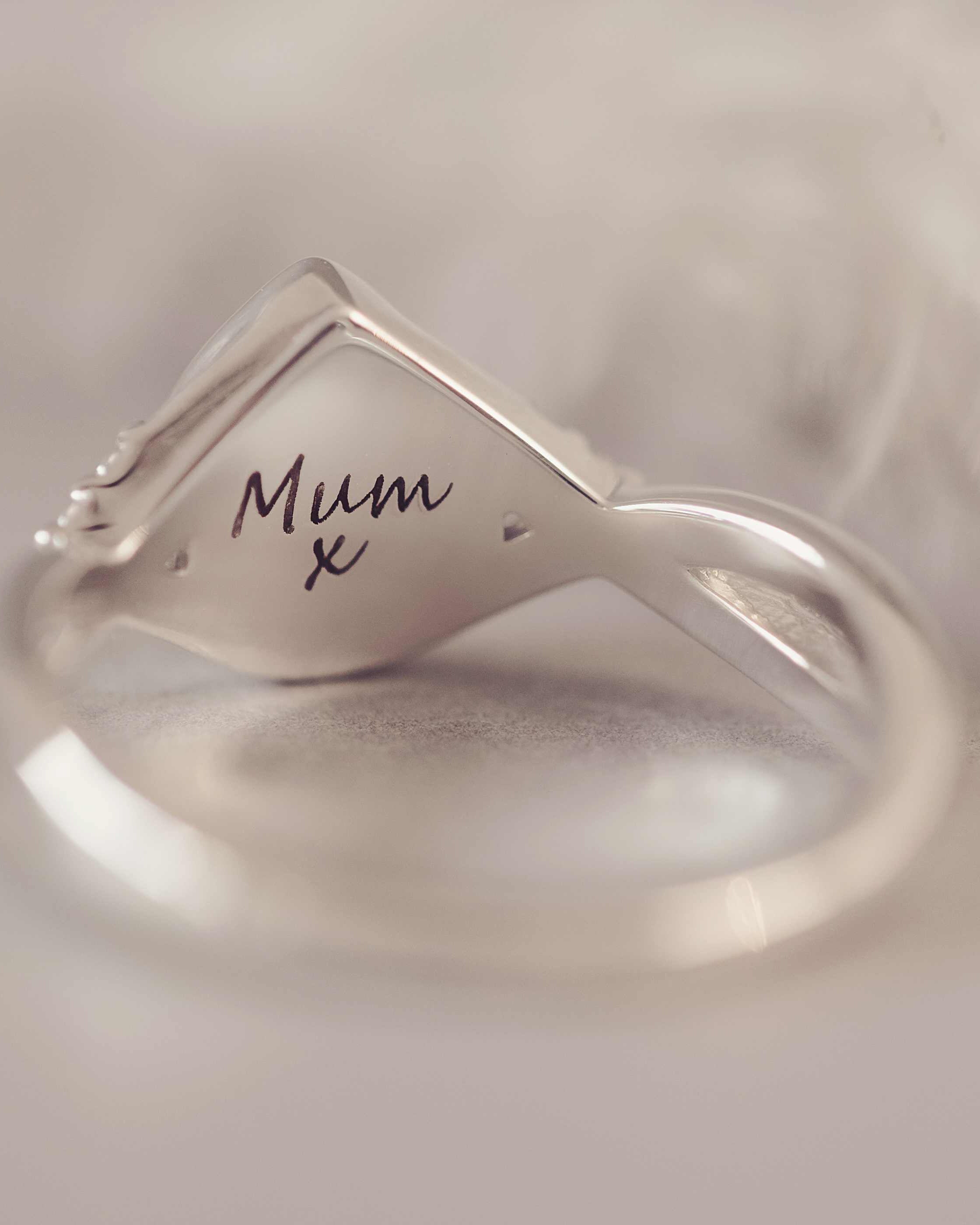 Silver ring with 'Mum x' engraving on a soft beige background