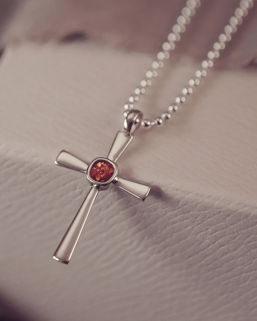 silver cross necklace holding cremation ashes, resin and orange crystal