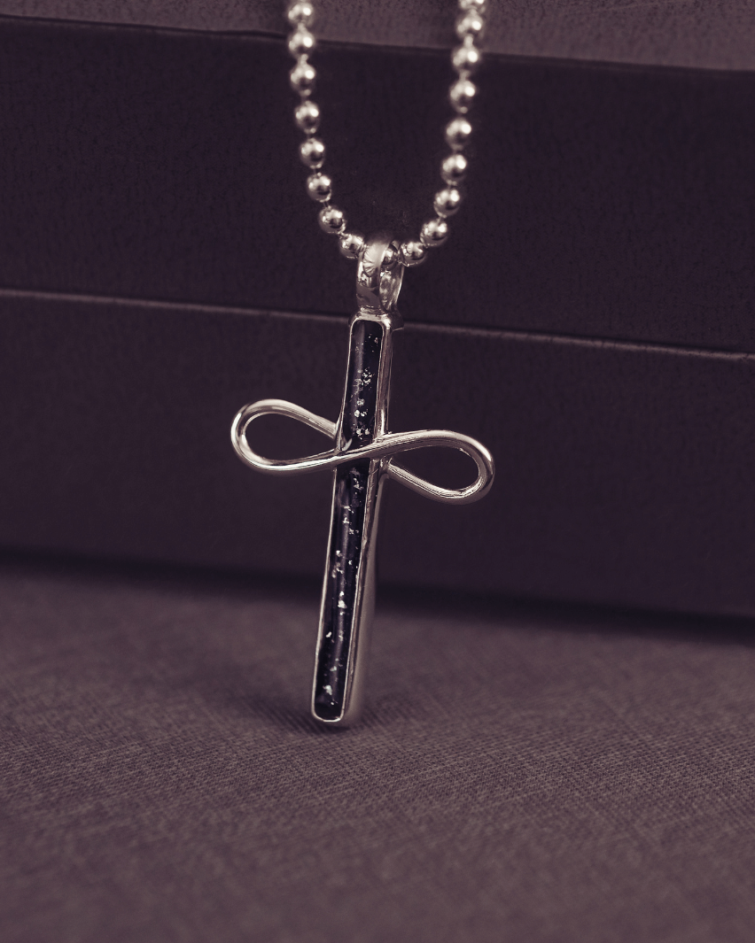 Silver cross pendant necklace on a dark background