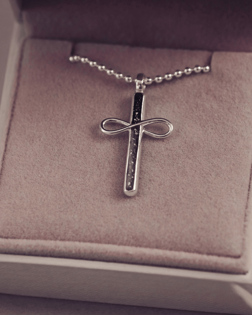 Silver cross necklace with chain on a cushion in a jewellery box