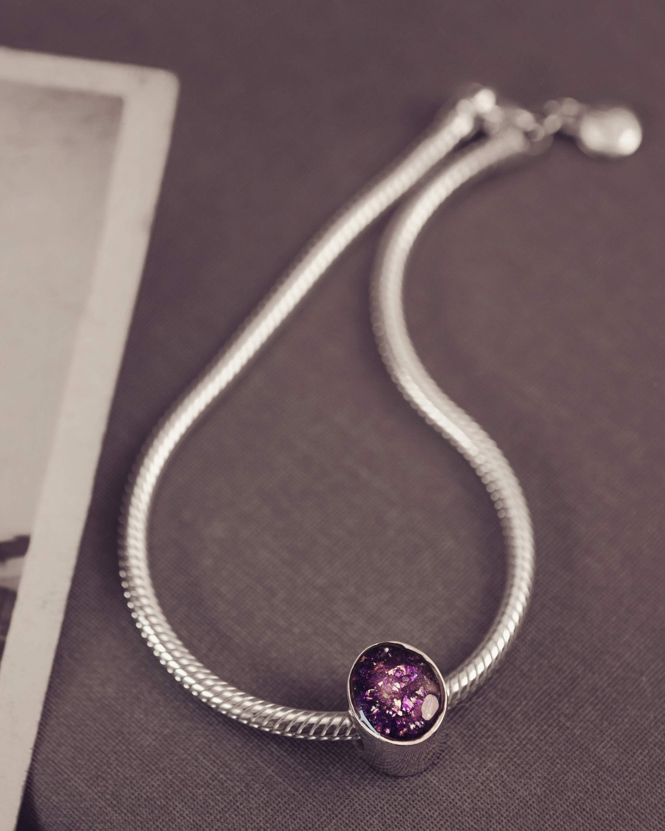 Silver bracelet with a purple gemstone on a textured surface