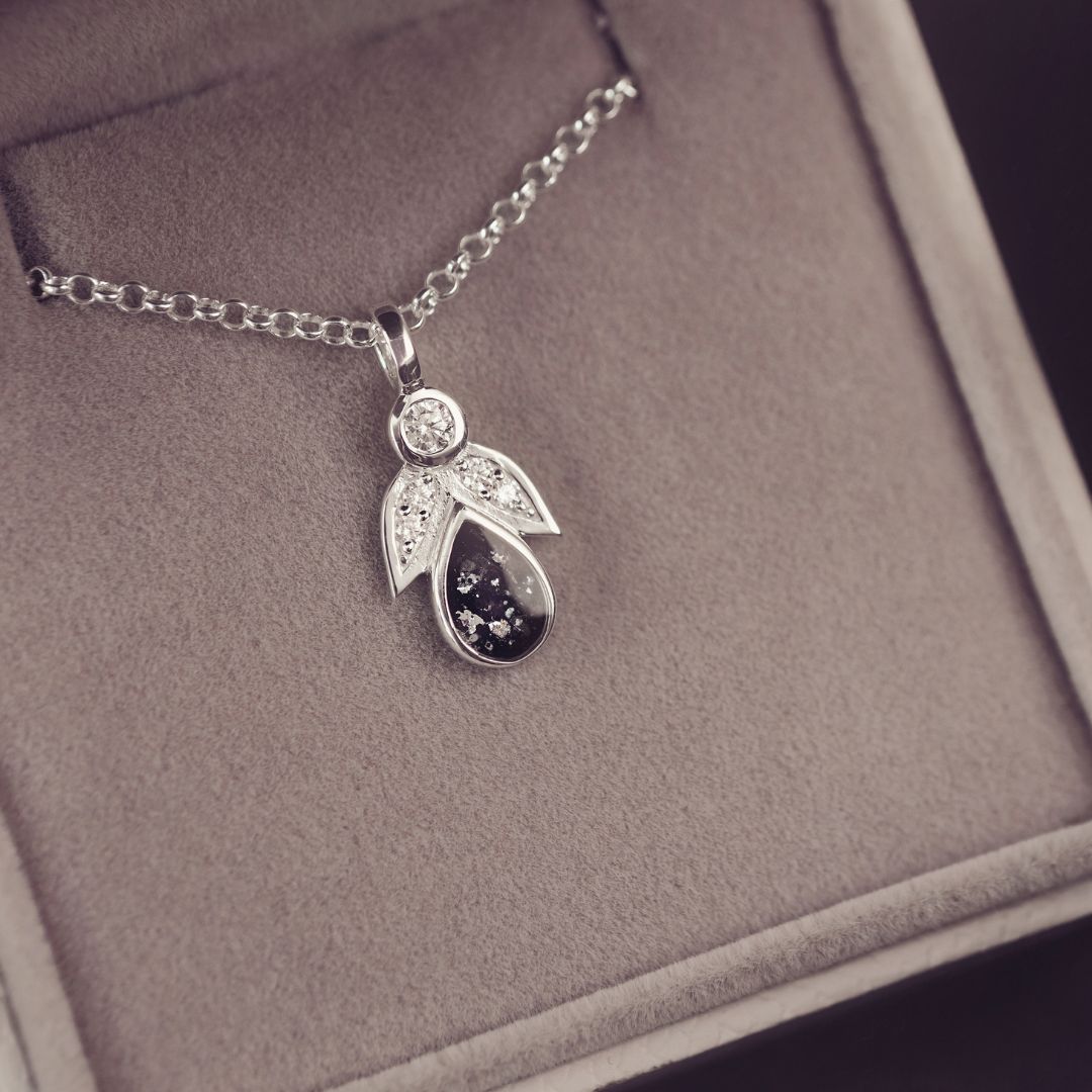 Silver pendant necklace on a gray cushioned jewelry box