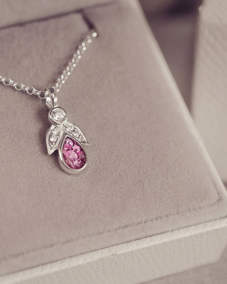 Silver necklace with a pink gemstone pendant on a soft gray background