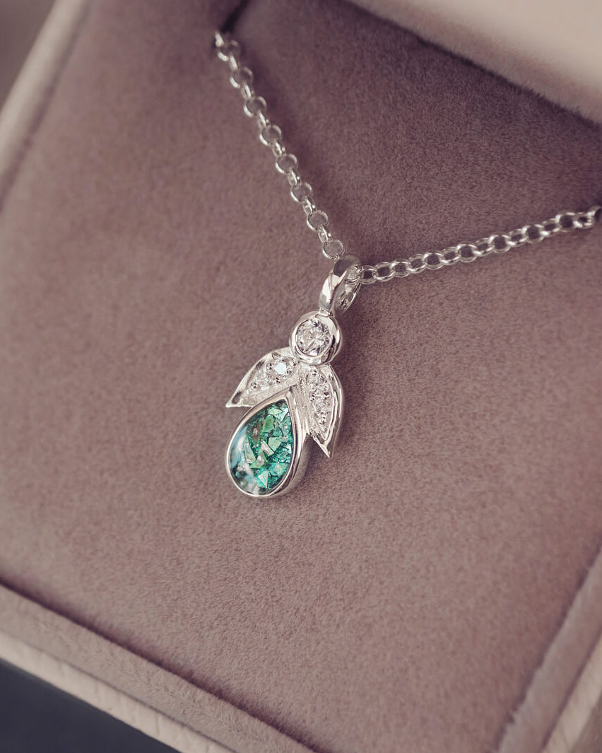 sterling silver angel pendant with green floating crystals sat in a jewellery box