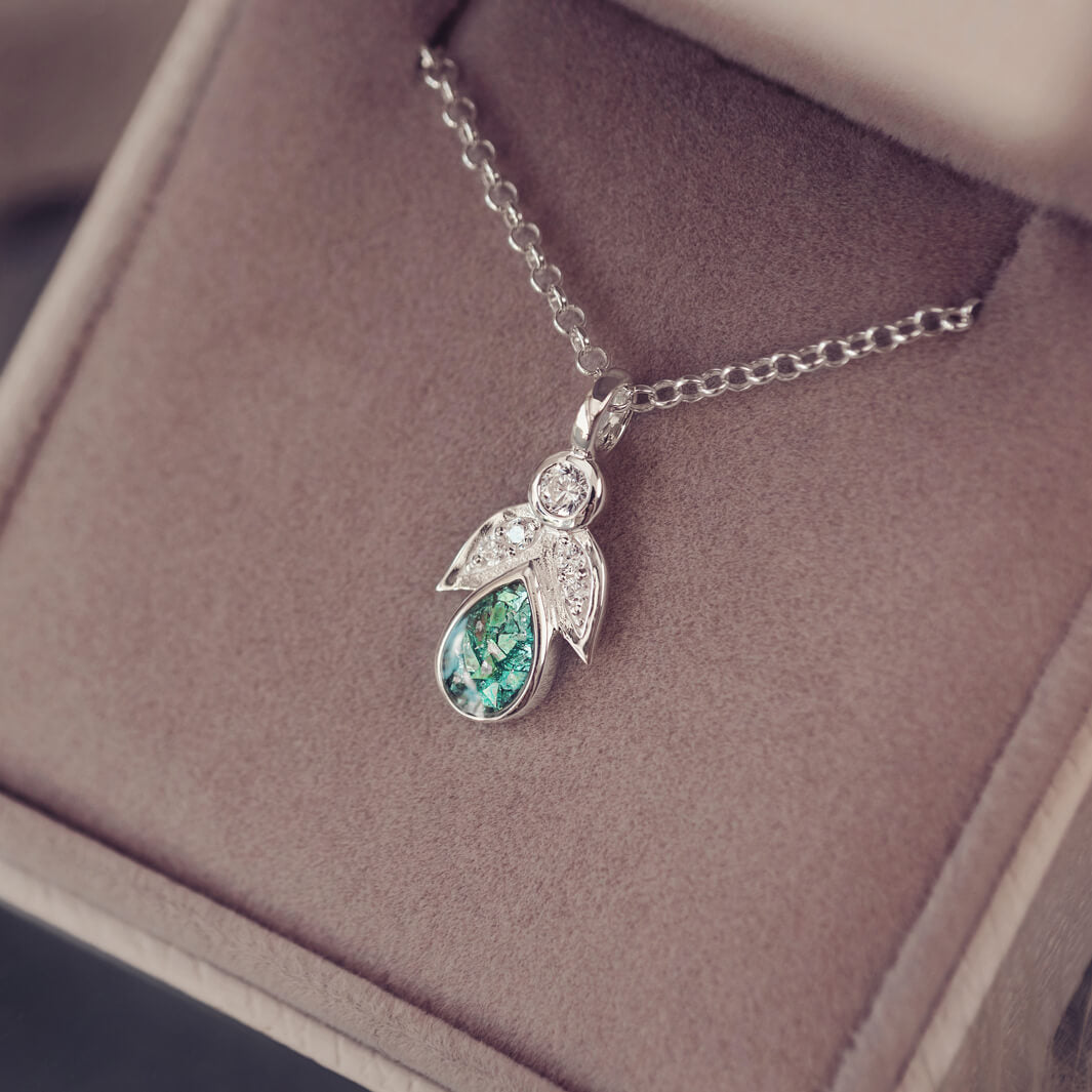 sterling silver angel pendant with green floating crystals sat in a jewellery box