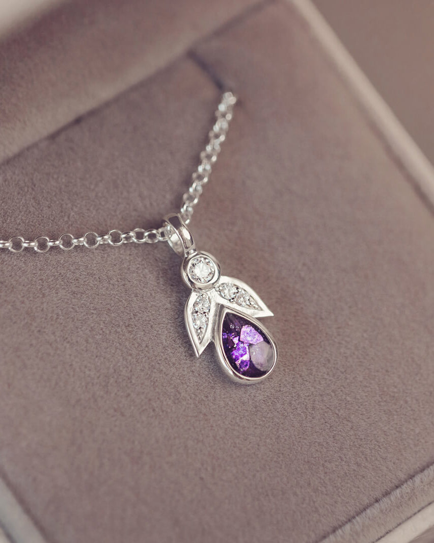 sterling silver angel pendant with purple floating crystals sat in a grey jewellery box
