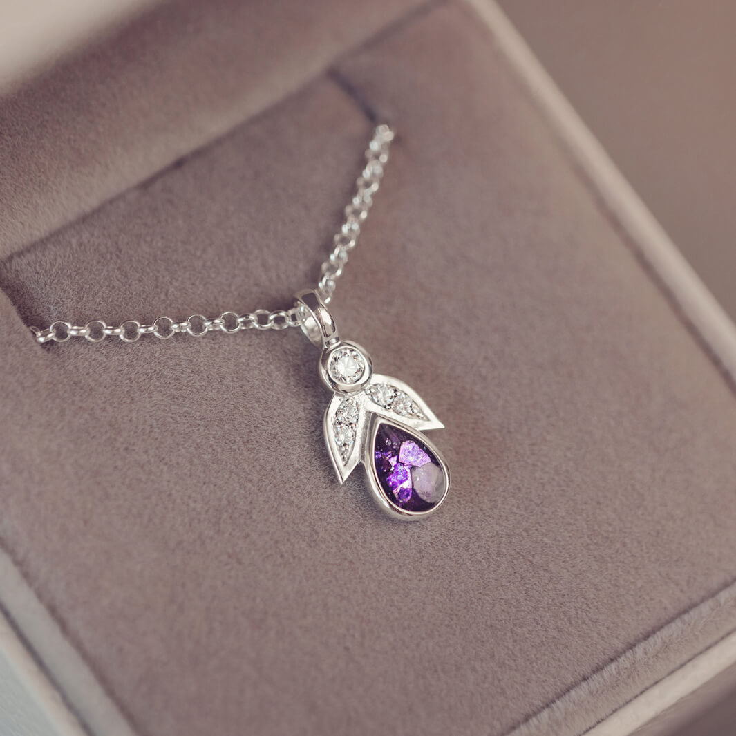 sterling silver angel pendant with purple floating crystals sat in a grey jewellery box