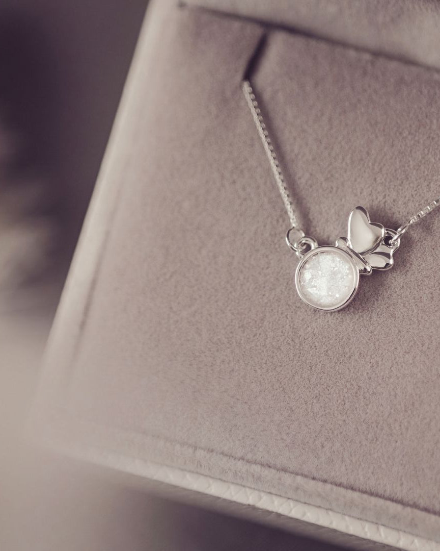 Silver necklace with a butterfly pendant on a soft fabric background