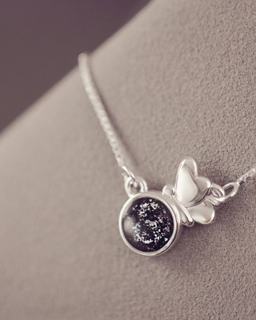 Silver necklace with a starry night pendant on a gray surface