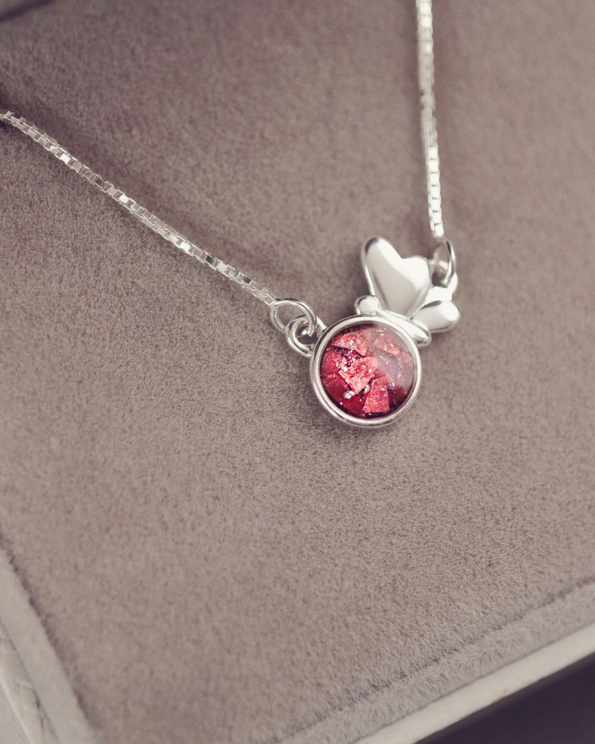 Silver necklace with a red pendant on a gray surface