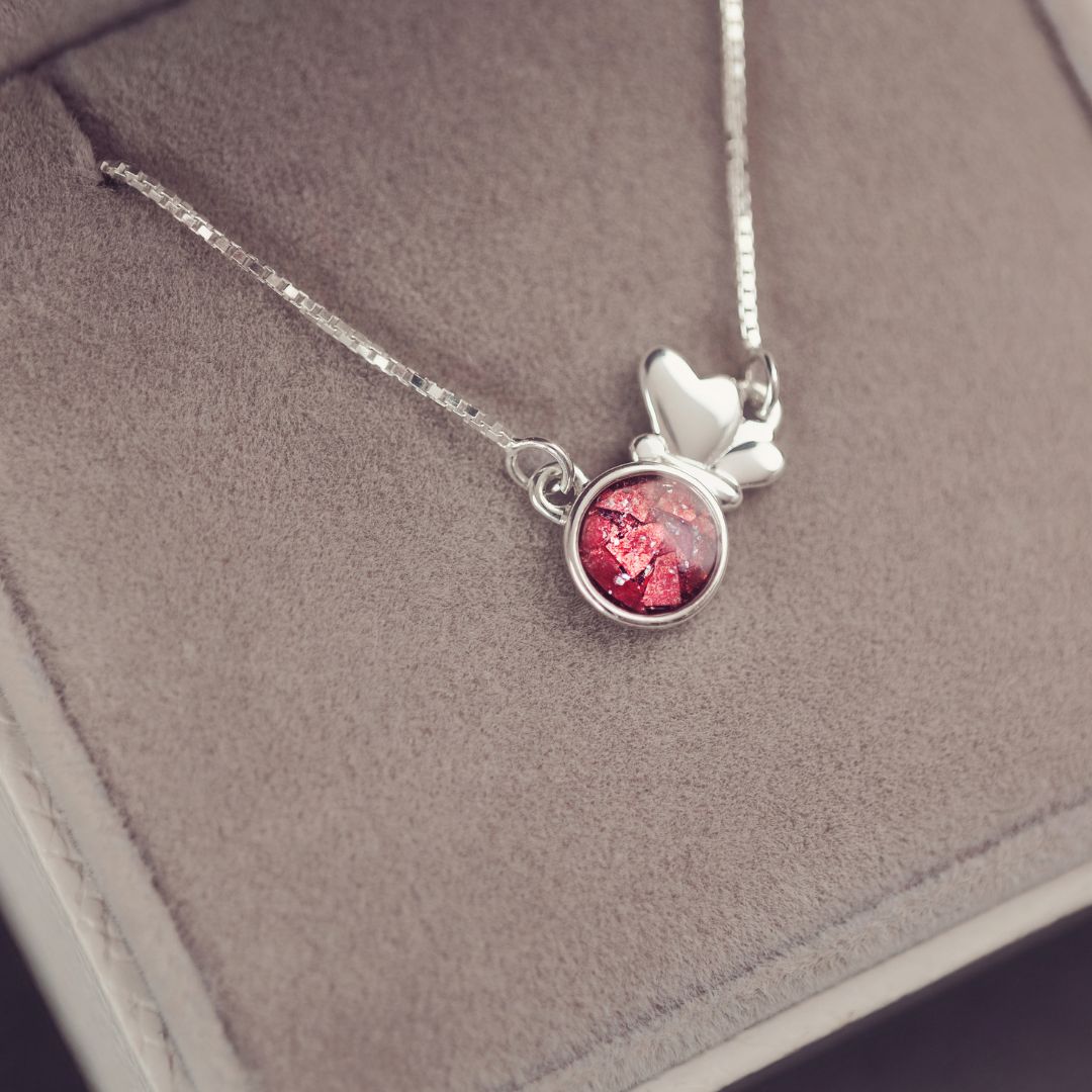 Silver necklace with a red pendant on a gray surface