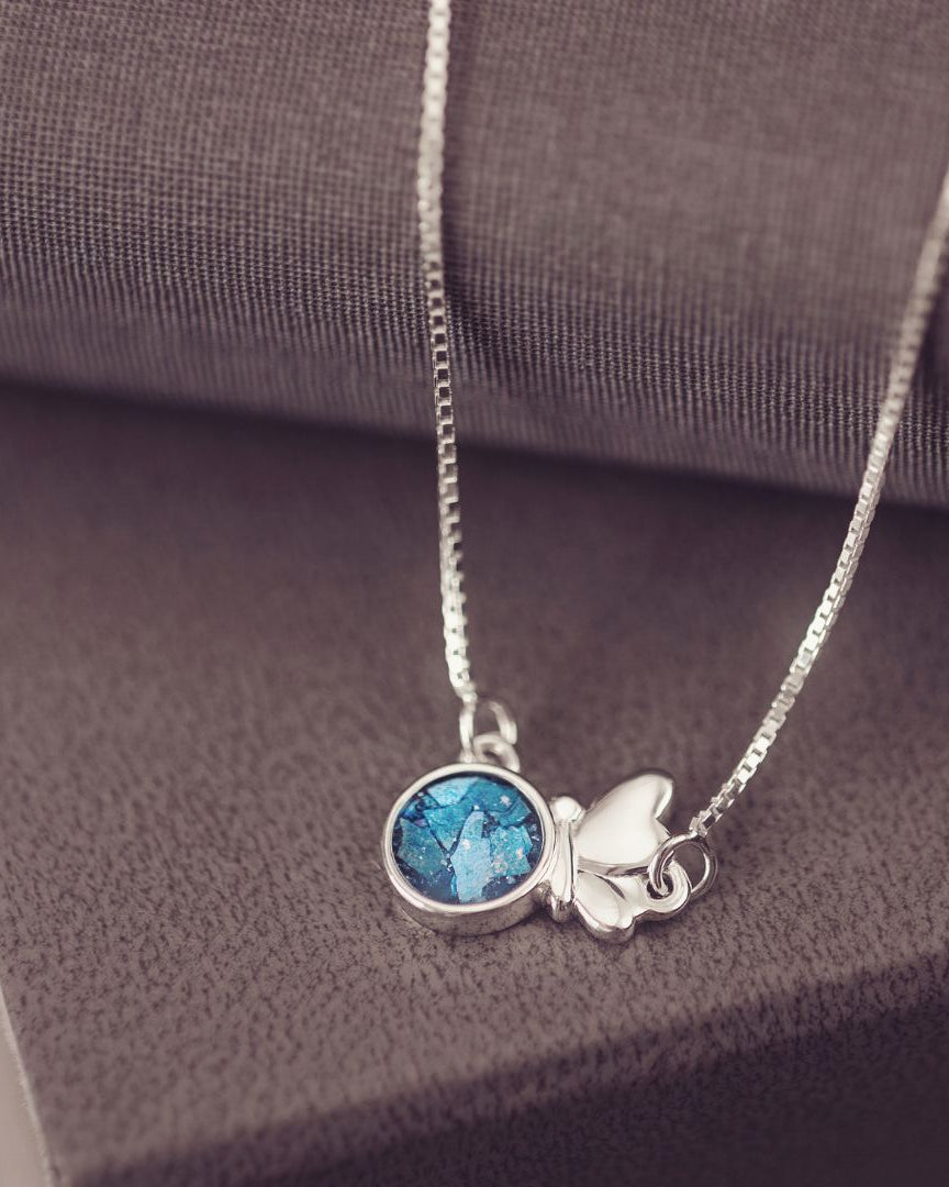 Silver necklace with a blue pendant on a textured surface