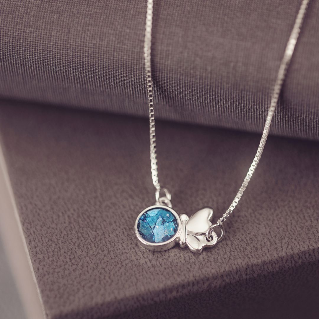 Silver necklace with a blue pendant on a textured surface