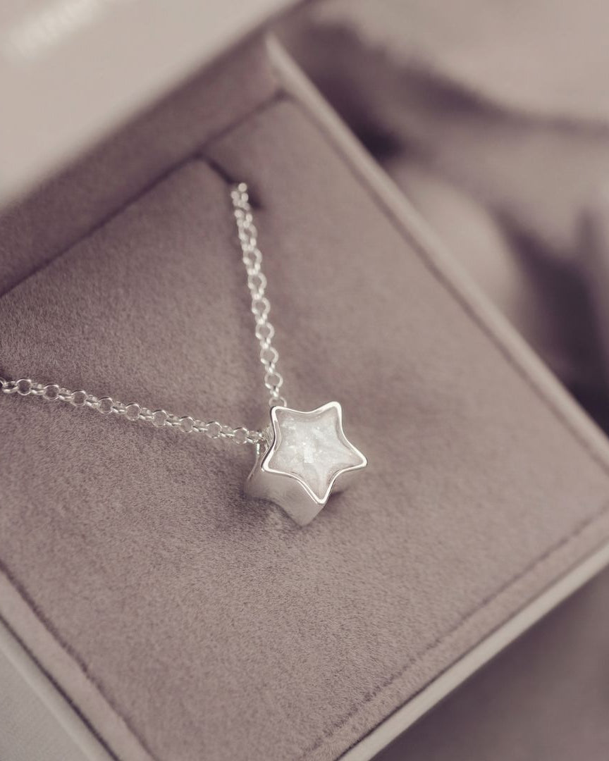 Silver star necklace on a soft gray surface