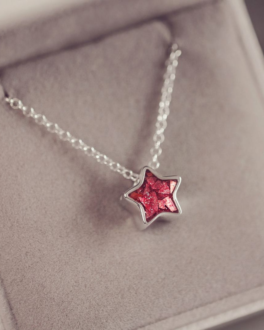 Star-shaped necklace with red gemstone on a soft surface