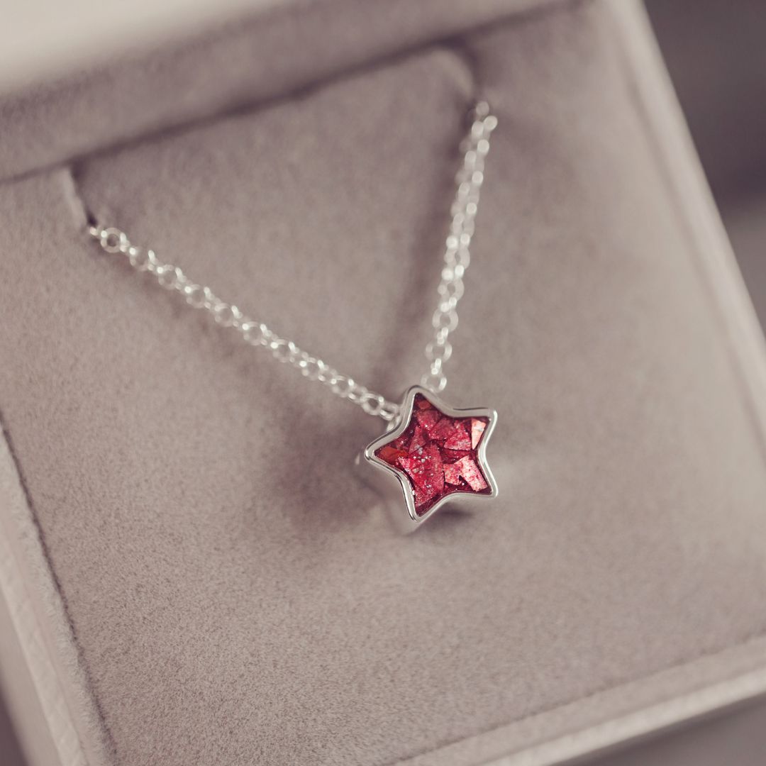 Star-shaped necklace with red gemstone on a soft surface