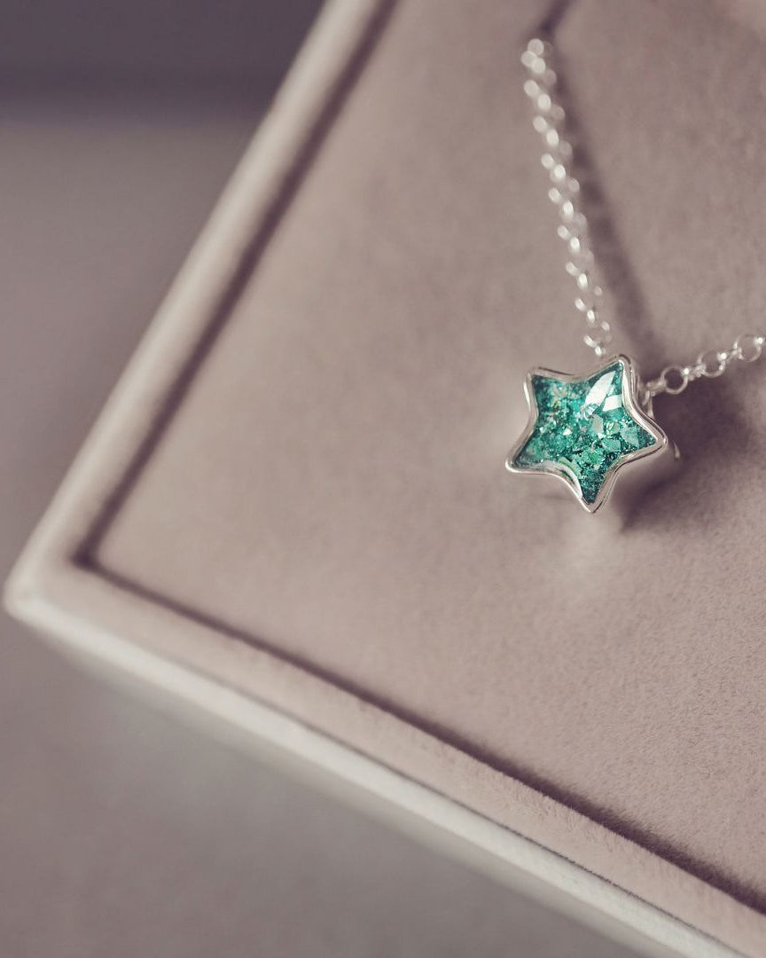 Star-shaped pendant necklace on a pink cushion