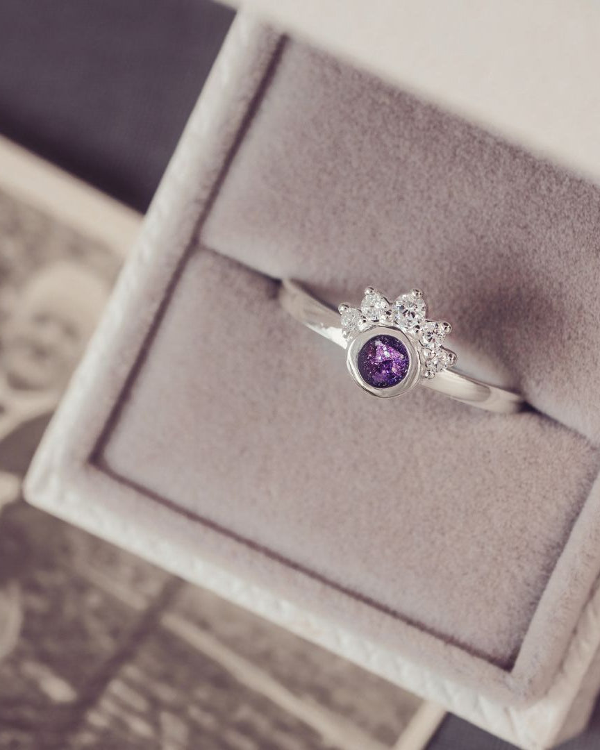 Silver ring with a purple gemstone in a jewelry box