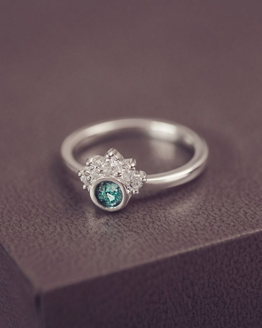 Silver ring with a green gemstone on a dark surface