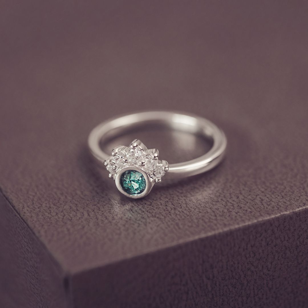 Silver ring with a green gemstone on a dark surface