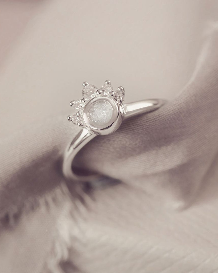 Silver ring with a central gemstone on a soft fabric background