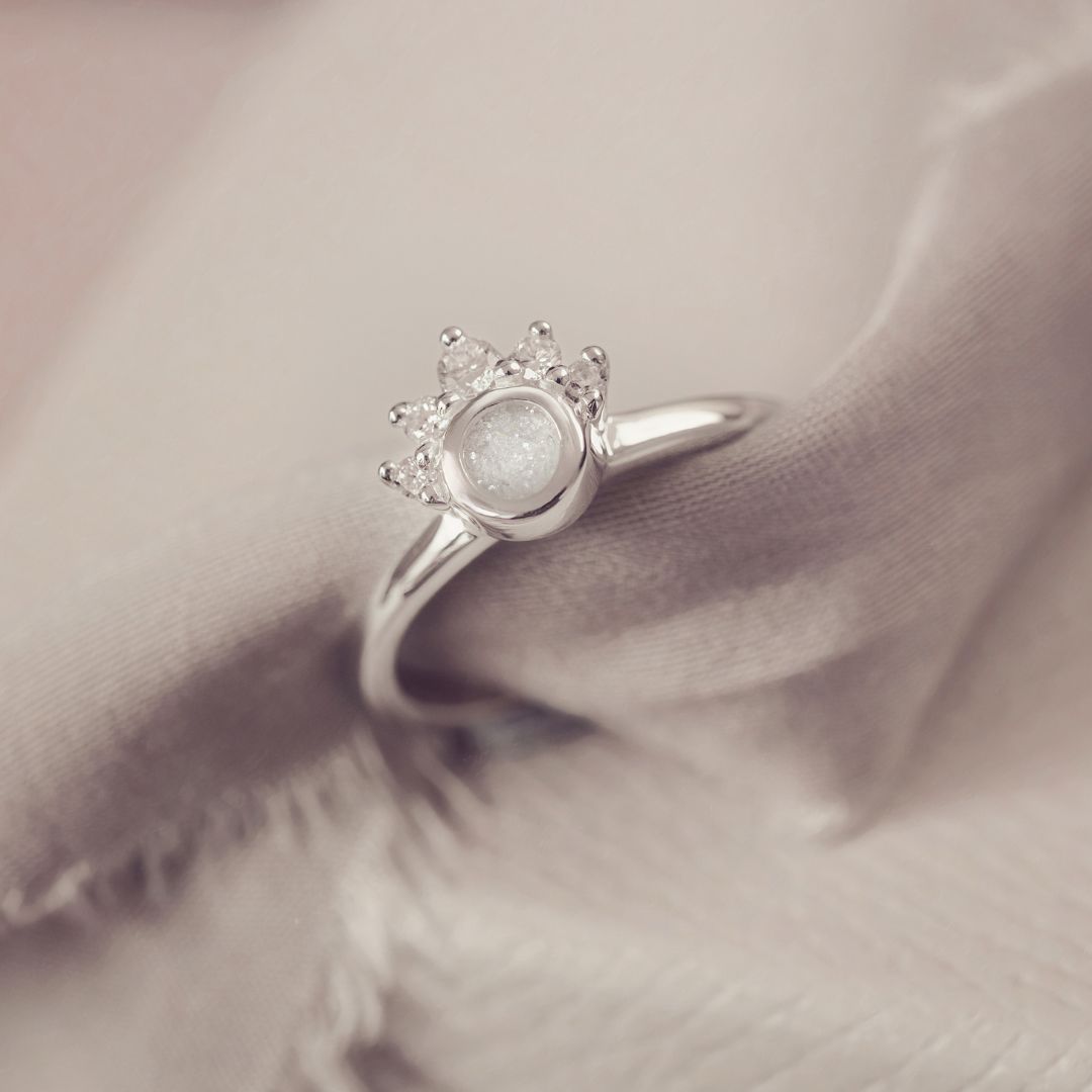 Silver ring with a central gemstone on a soft fabric background