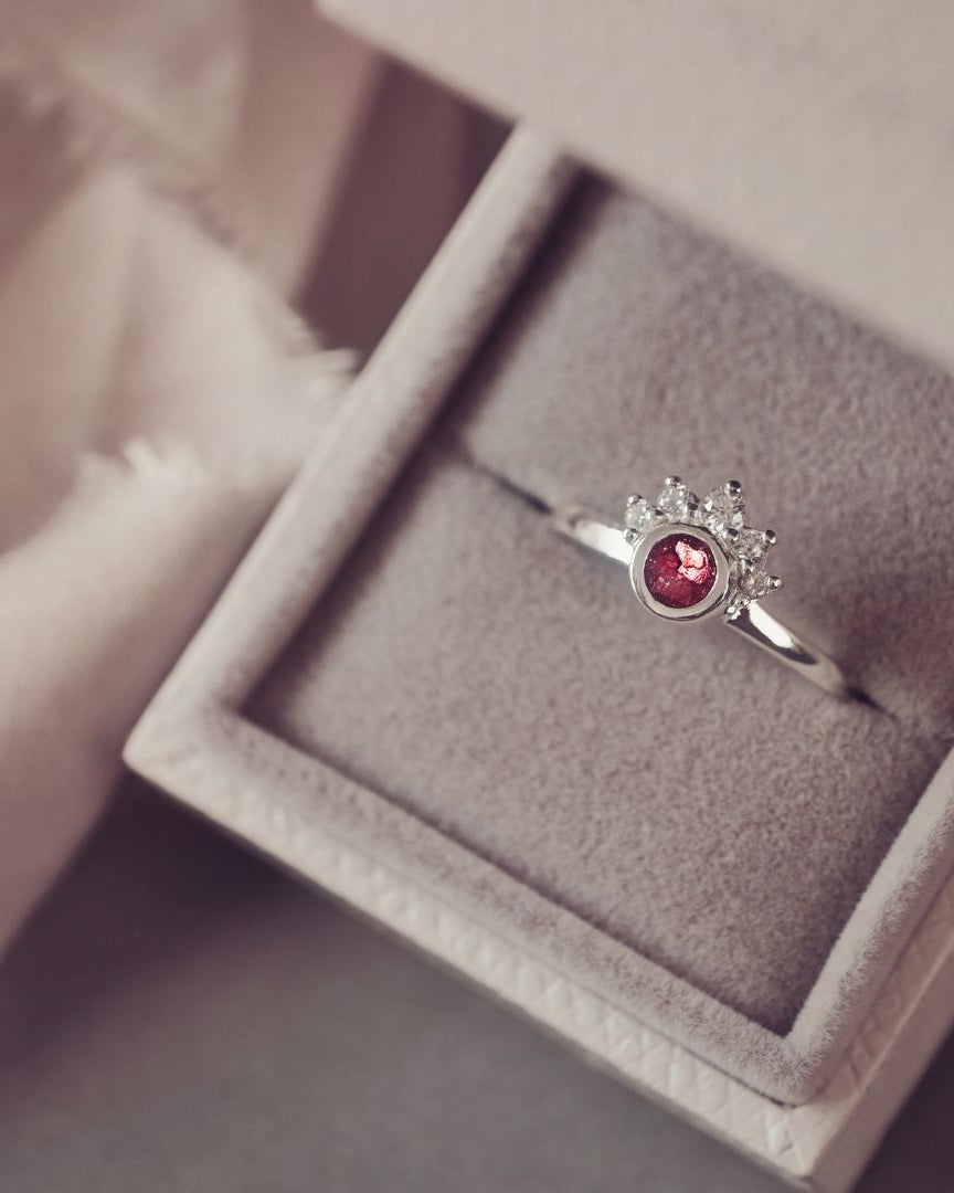 Silver ring with a red gemstone in a jewelry box