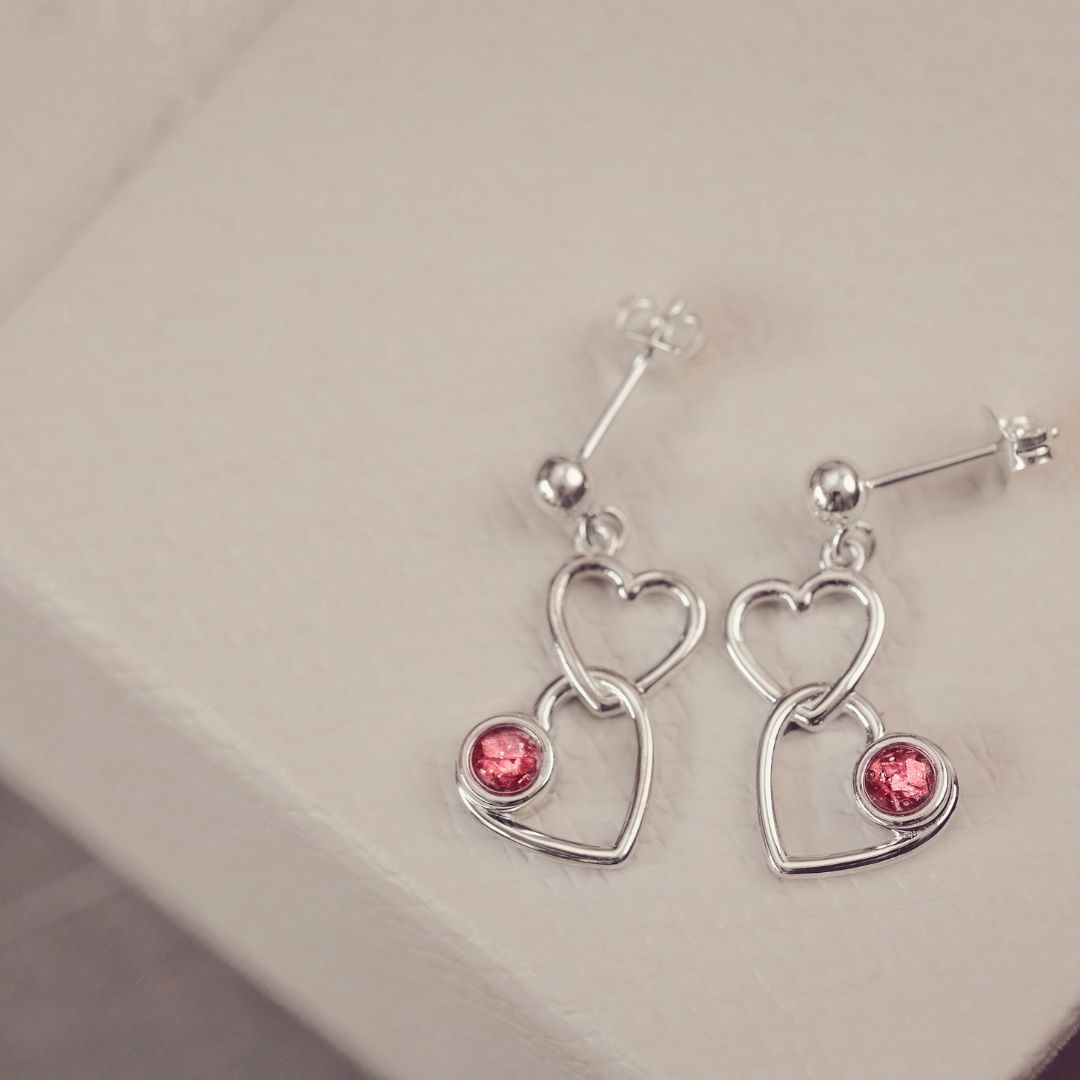 Two silver heart dangle earrings with red gemstones