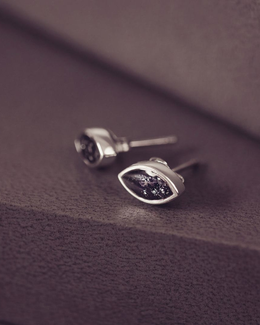 Silver earrings with purple gemstones on a textured purple surface