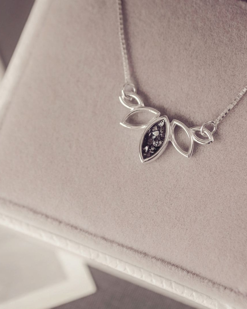 Silver necklace with leaf-shaped pendant on a soft surface
