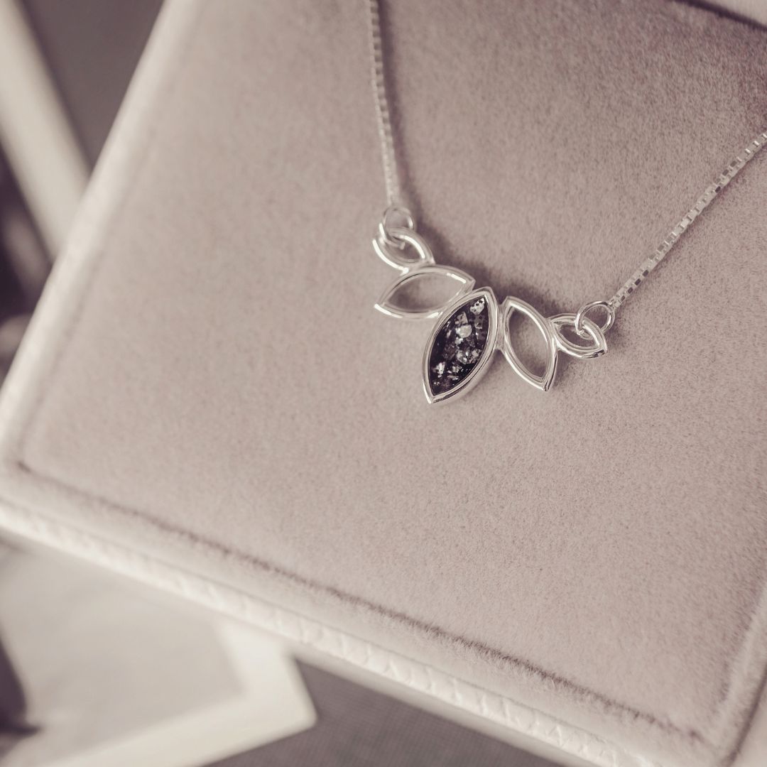 Silver necklace with leaf-shaped pendant on a soft surface