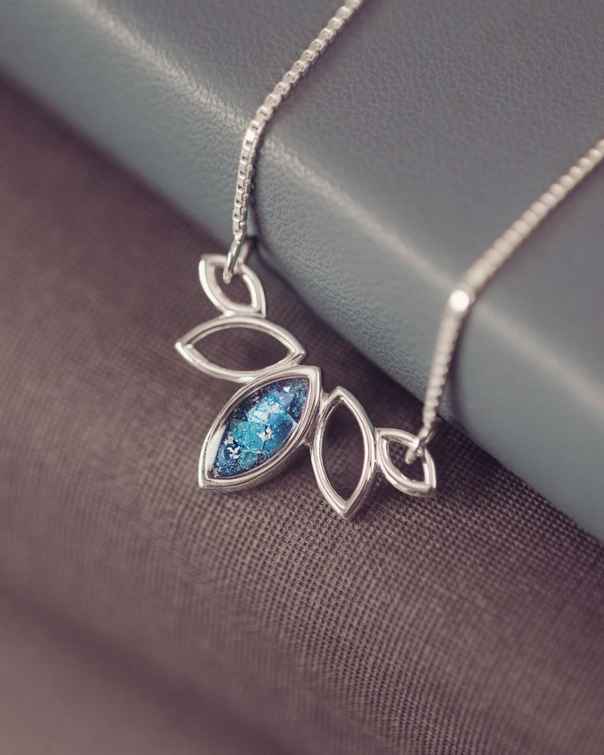 Silver necklace with a blue gemstone pendant on a textured surface