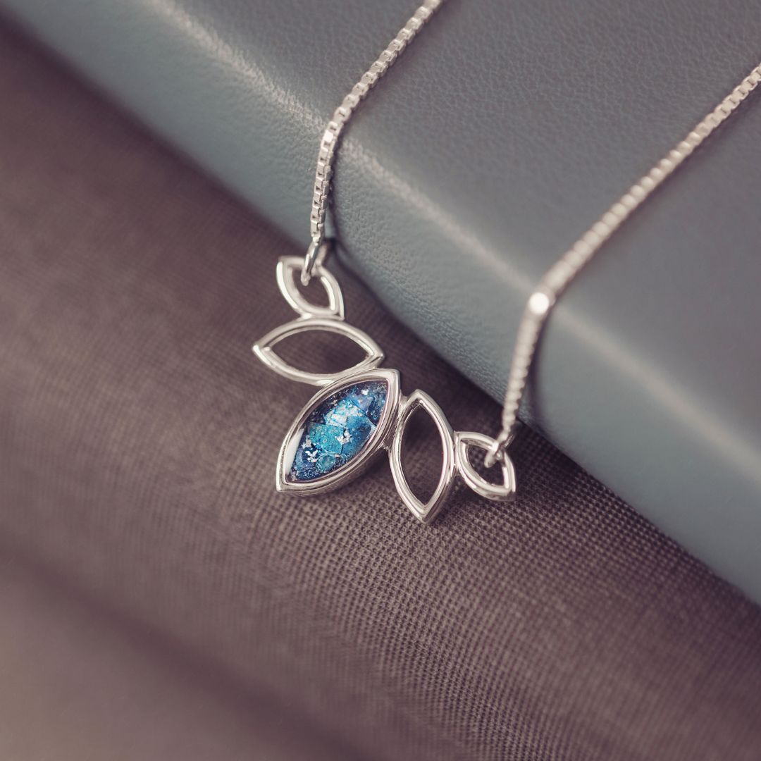Silver necklace with a blue gemstone pendant on a textured surface